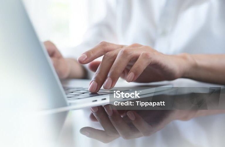 Close up of business woman hand typing on laptop computer keyboard with reflection on digital tablet on office table, online working, surfing the internet, distant job, remote work concept